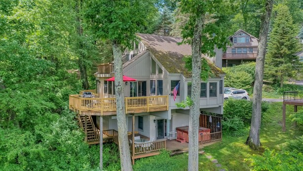 Une cabane à deux étages dotée d’une terrasse, entourée d’une forêt dense.