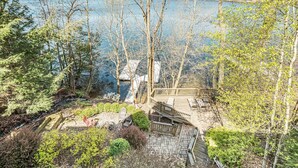 A deck with outdoor seating overlooking a lake, surrounded by trees and shrubs. - Sunset Pointe by Taylor Made Deep Creek (Oakland)