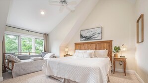 A bedroom with a large bed, a smaller bed, a ceiling fan, a window with curtains, a bedside table with a lamp, and a framed picture on the wall. - Sunset Pointe by Taylor Made Deep Creek (Oakland)