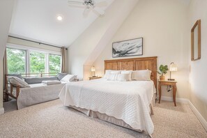 A bedroom with a large bed, a smaller bed, a ceiling fan, a window with curtains, a bedside table with a lamp, and a framed picture on the wall. - Sunset Pointe by Taylor Made Deep Creek (Oakland)