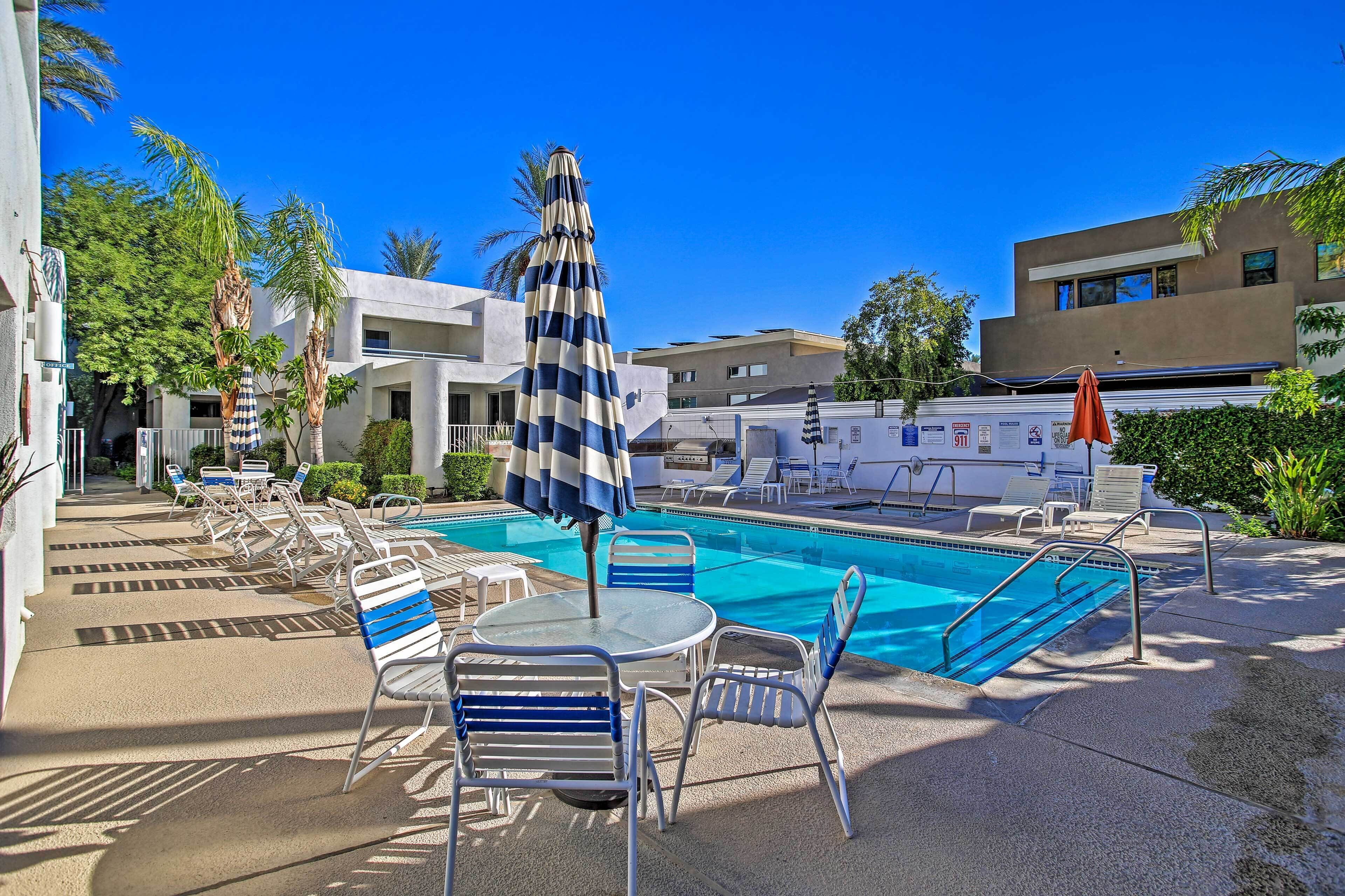 A pool area with lounge chairs, umbrellas, and a clear blue sky.