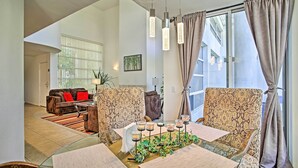 A modern living room with a glass table, patterned sofas, and a view of the outside.