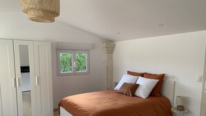 A bedroom with a bed, wardrobe, window, and a lamp. - Studio Le soleil couchant, in Provence near Avignon (Saint-Saturnin-lès-Avignon)
