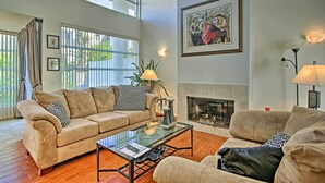 Un salón amplio con un sofá color beige, una mesa de centro de cristal y una chimenea.