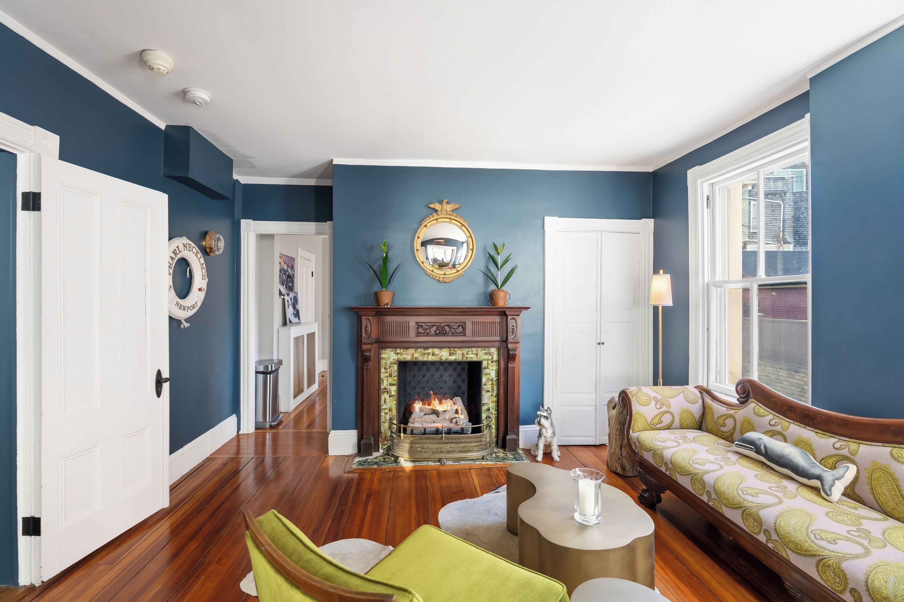 A living room with a fireplace, a sofa, a green chair, and a small table.