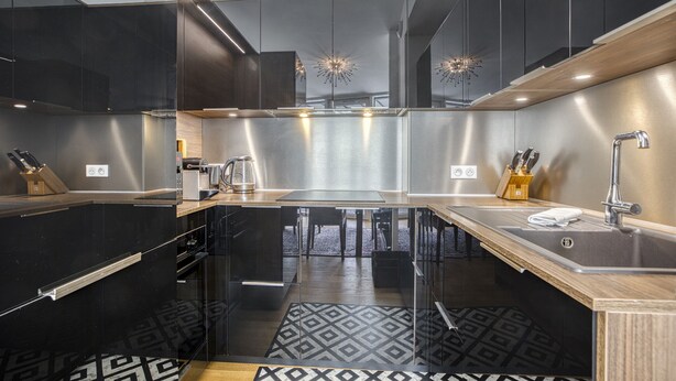 Una cocina moderna con armarios oscuros, electrodomésticos de acero inoxidable y encimera de madera.
