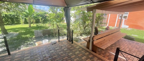 Relax in the serene garden view from this patio, complete with a comfortable bench and shaded seating area.