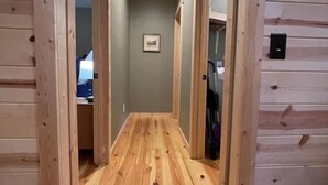 Ein Korridor mit Holzwänden und -böden, einer Deckenleuchte und einem gerahmten Bild an der Wand.
