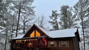Eine Blockhütte mit Veranda, einer Flagge und verschneitem Gelände.