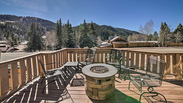 Une terrasse en bois avec des meubles d’extérieur, un foyer et une vue sur un paysage montagneux.