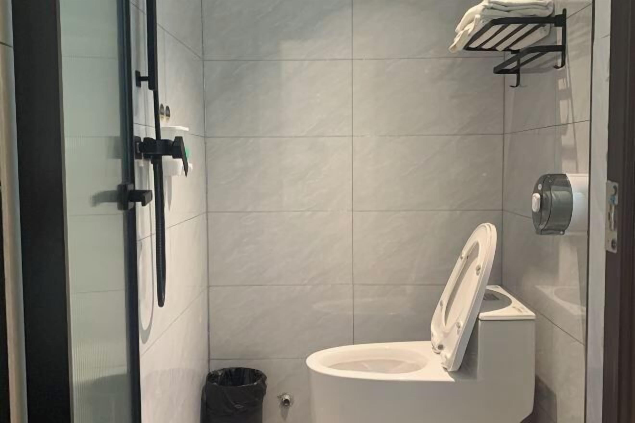Un baño moderno con inodoro blanco, cabina de ducha de vidrio y toallero negro.