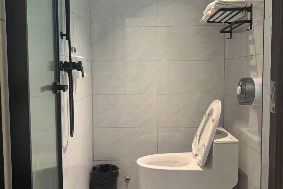 A modern bathroom with a white toilet, a glass shower enclosure, and a black towel rack.