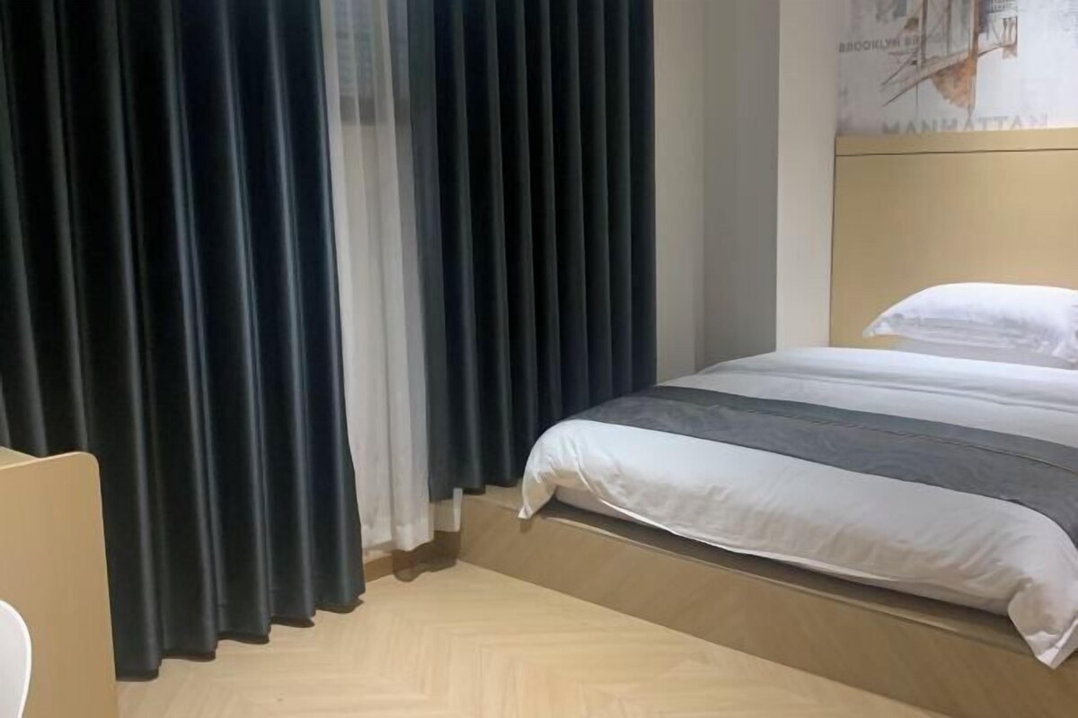 A hotel room with a bed, a headboard, and a curtain.