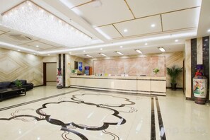 A hotel lobby with a reception desk, seating area, and a decorative floor pattern. - Jiaxi Hotel (Tongliao)