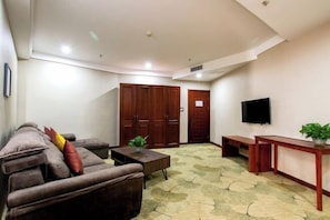 A living room with a sofa, a coffee table, a TV, and a wooden door. - Jiaxi Hotel (Tongliao)