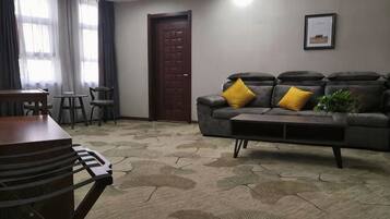 A living room with a sofa, a coffee table, a dining table, and chairs.