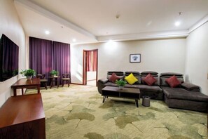 A living room with a sofa, coffee table, and a TV. - Jiaxi Hotel (Tongliao)