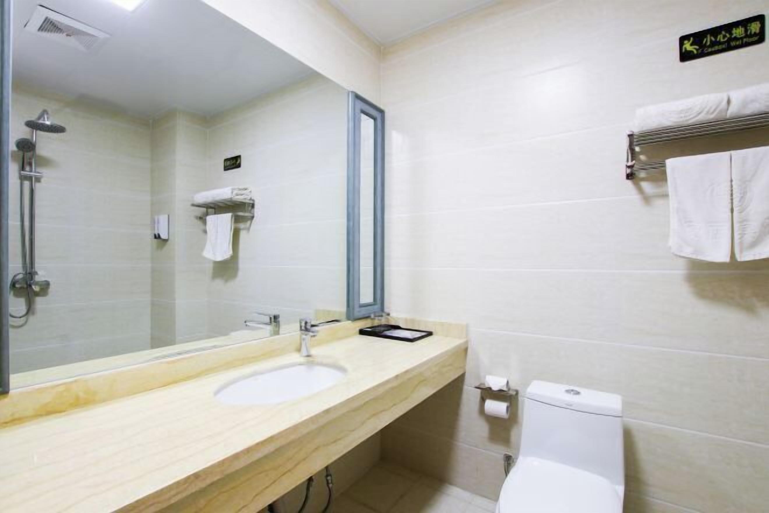 Uma casa de banho com lavatório, espelho, porta-toalhas e sanita.