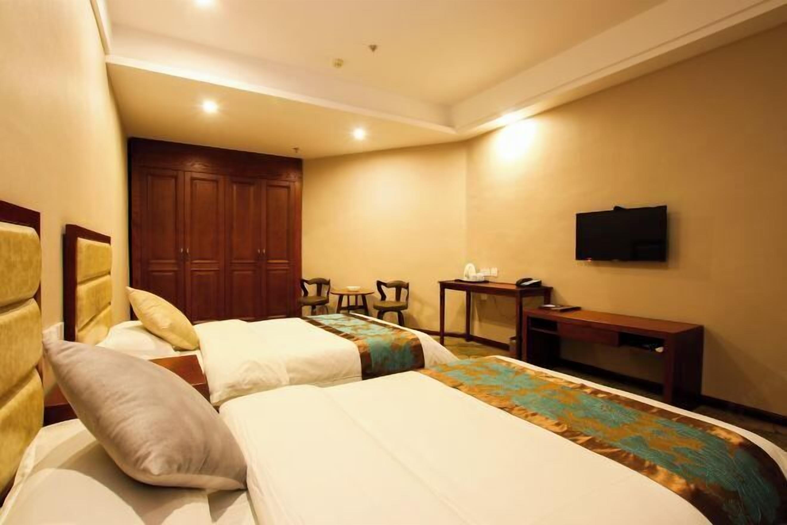 A hotel room with two beds, a TV, a desk, and a wardrobe.