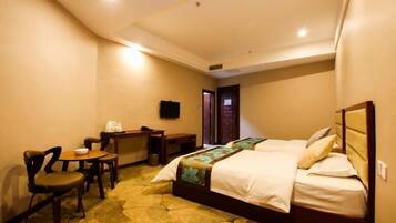 A hotel room with two beds, a desk with a chair, a television, and a carpeted floor.