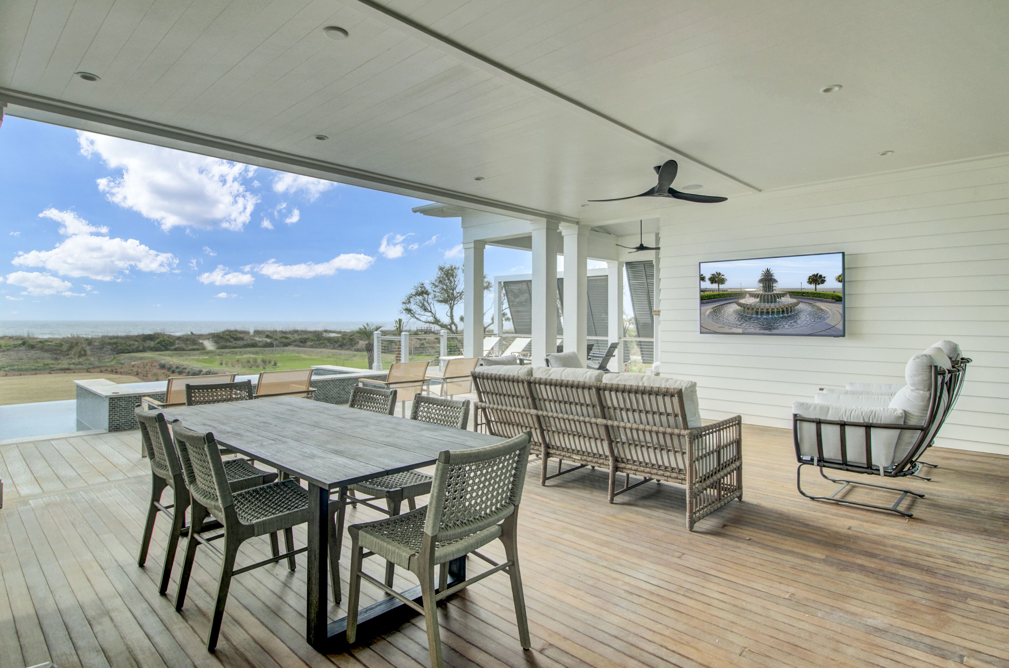 Un patio techado al aire libre con una mesa y sillas de comedor, un sofá y una silla colgante.
