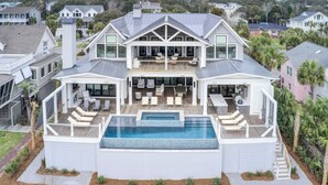 A large, modern two-story house with a large deck and a swimming pool.