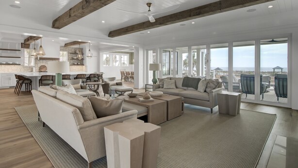 A spacious living room with a large sofa, coffee table, and a view of the city through large windows.