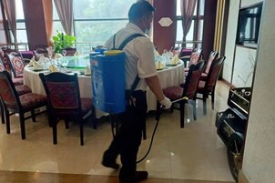 Una persona limpiando un comedor con un equipo de limpieza azul grande.