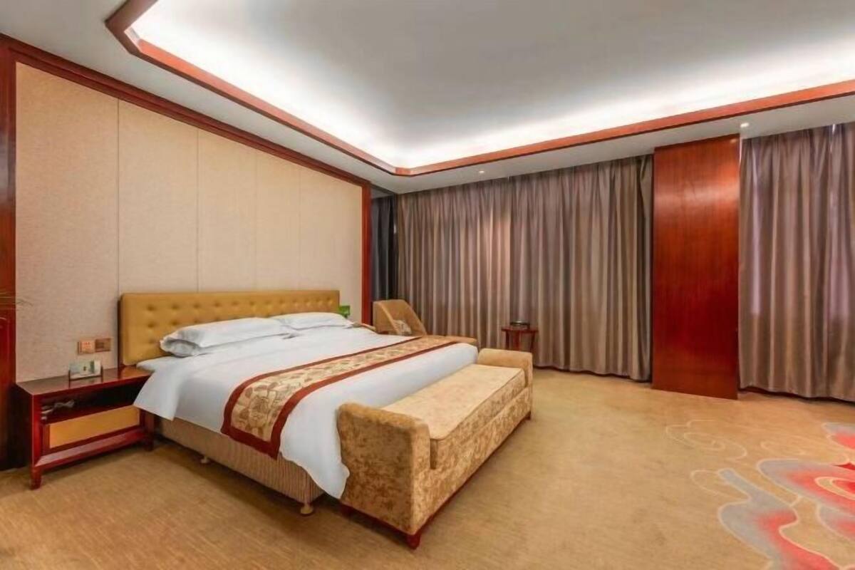A hotel room with a bed, a bench, a nightstand, and a wardrobe.