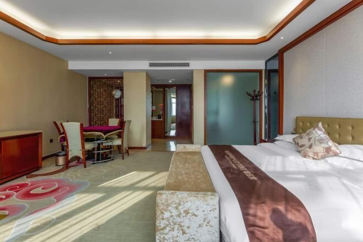 A hotel room with a bed, a desk, a chair, and a carpet with a floral pattern.