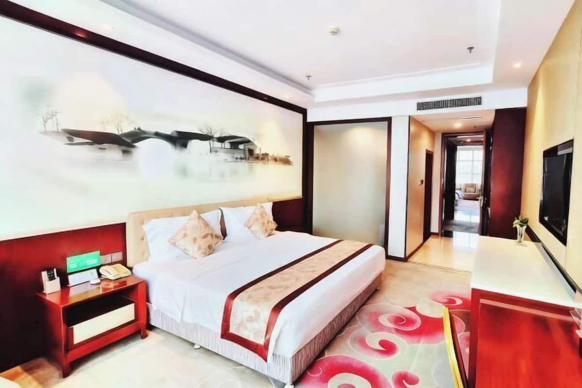A hotel room with a bed, bedside table, and a TV.
