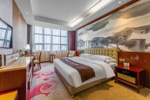Habitación de hotel con una cama grande, un escritorio, una silla y un cuadro en la pared.