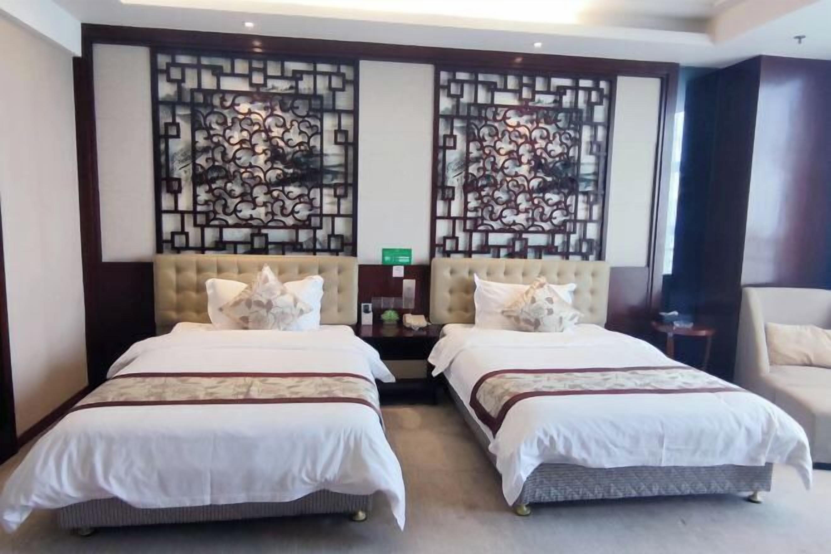 Une chambre d’hôtel avec deux lits, une tête de lit décorative, une petite table et une chaise.