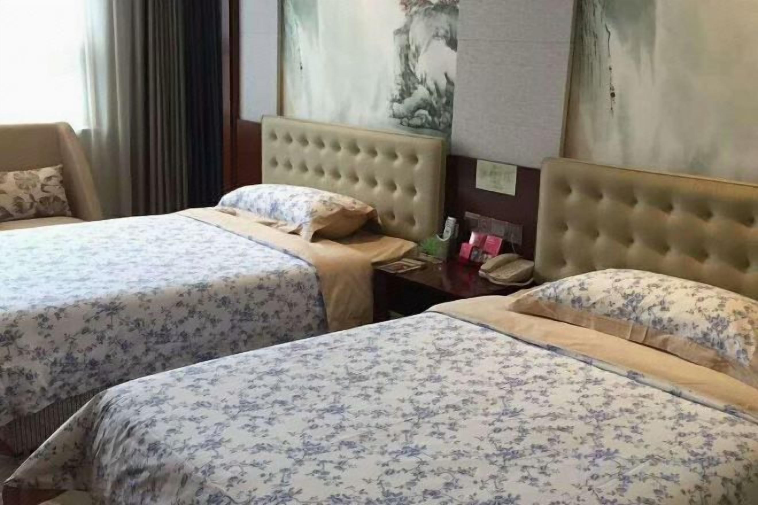Quarto de hotel com duas camas, cabeceira, mesa de cabeceira e um quadro na parede.
