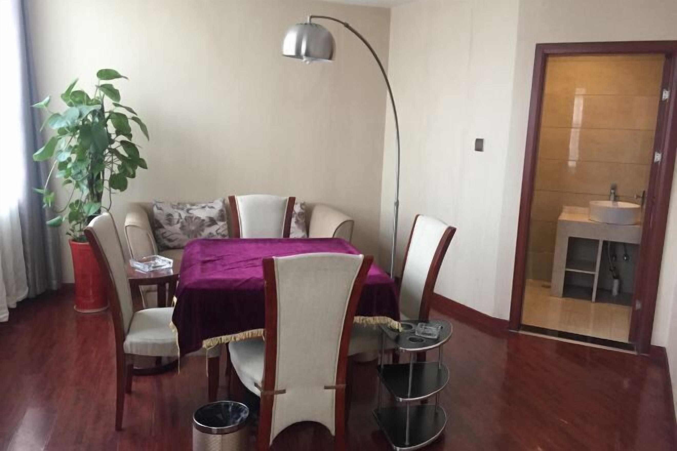 Un comedor con una mesa, sillas, una planta, una lámpara y vistas al baño.