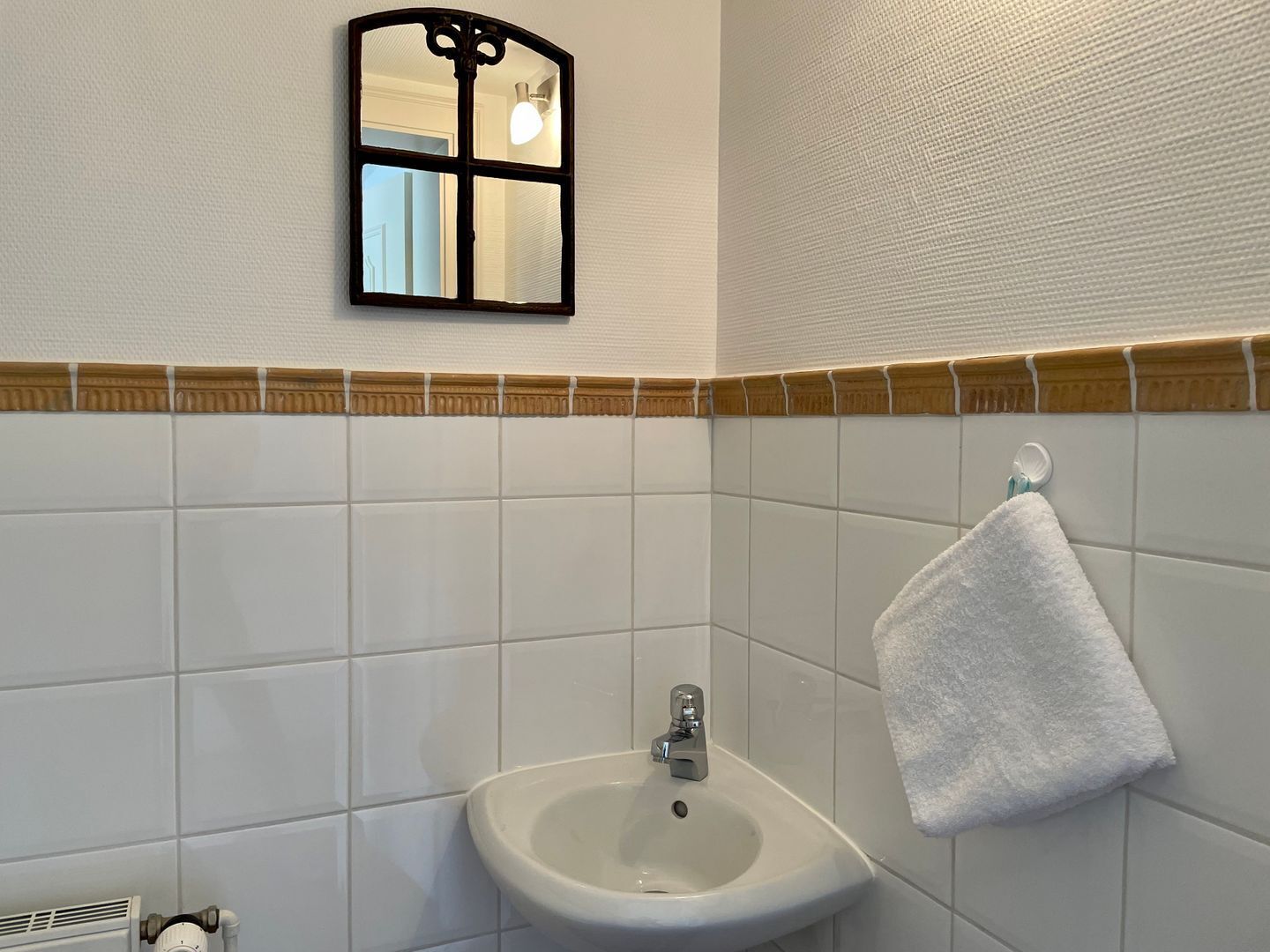 A bathroom with a white sink, a towel hanging on the wall, and a mirror above the sink.