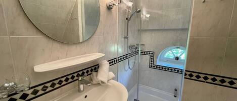 A bathroom with a round mirror, a sink, a shower enclosure, and a bathtub.