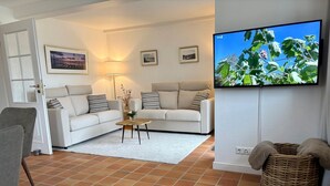 A living room with two white sofas, a coffee table, a TV, and a wicker basket.