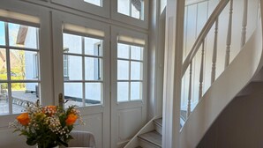 Ein Zimmer mit einem runden Tisch, einer Topfpflanze und einer Treppe mit weißen Geländern.