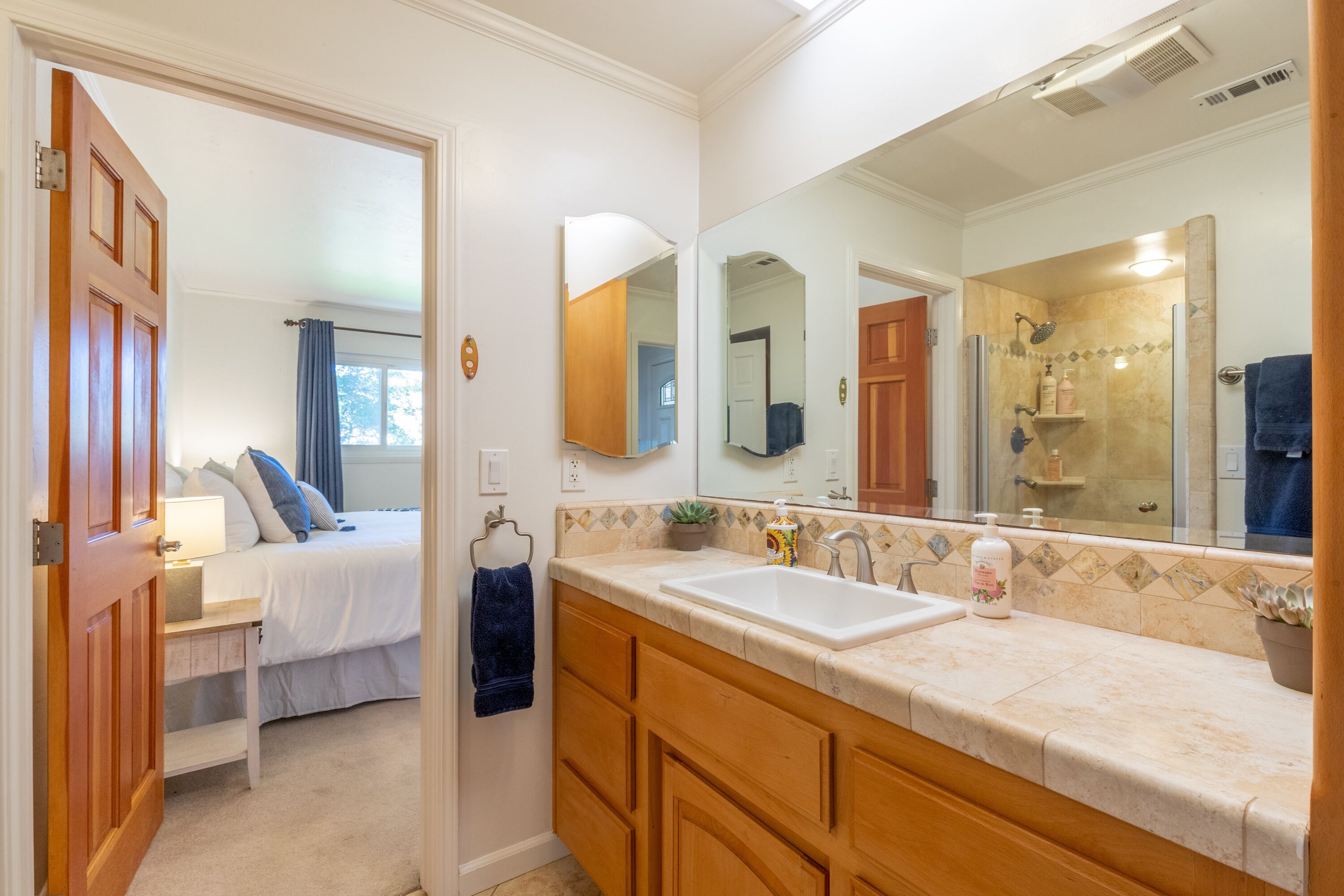 A bathroom with a large mirror, a sink, and a shower area.