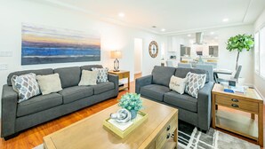 A modern living room with two grey sofas, a wooden coffee table, and a large abstract painting on the wall.