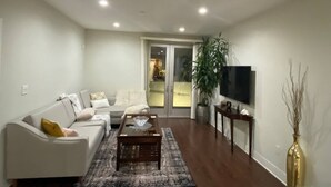 Ein Wohnzimmer mit einer Couch, einem Couchtisch und einem Fernseher auf einem Schrank.