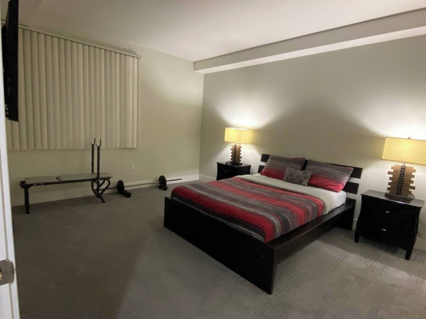 Ein Schlafzimmer mit einem Bett, zwei Nachttischen mit Lampen, einer Bank und einer Heizung.