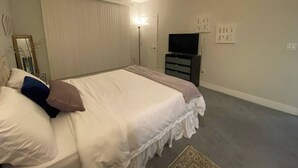 Ein Schlafzimmer mit einem Bett, einem Fernseher, einer Kommode und einer Wand mit den Schildern 'LOVE' und 'HOPE'.