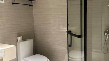A modern bathroom with a toilet, a glass shower enclosure, and a towel rack.