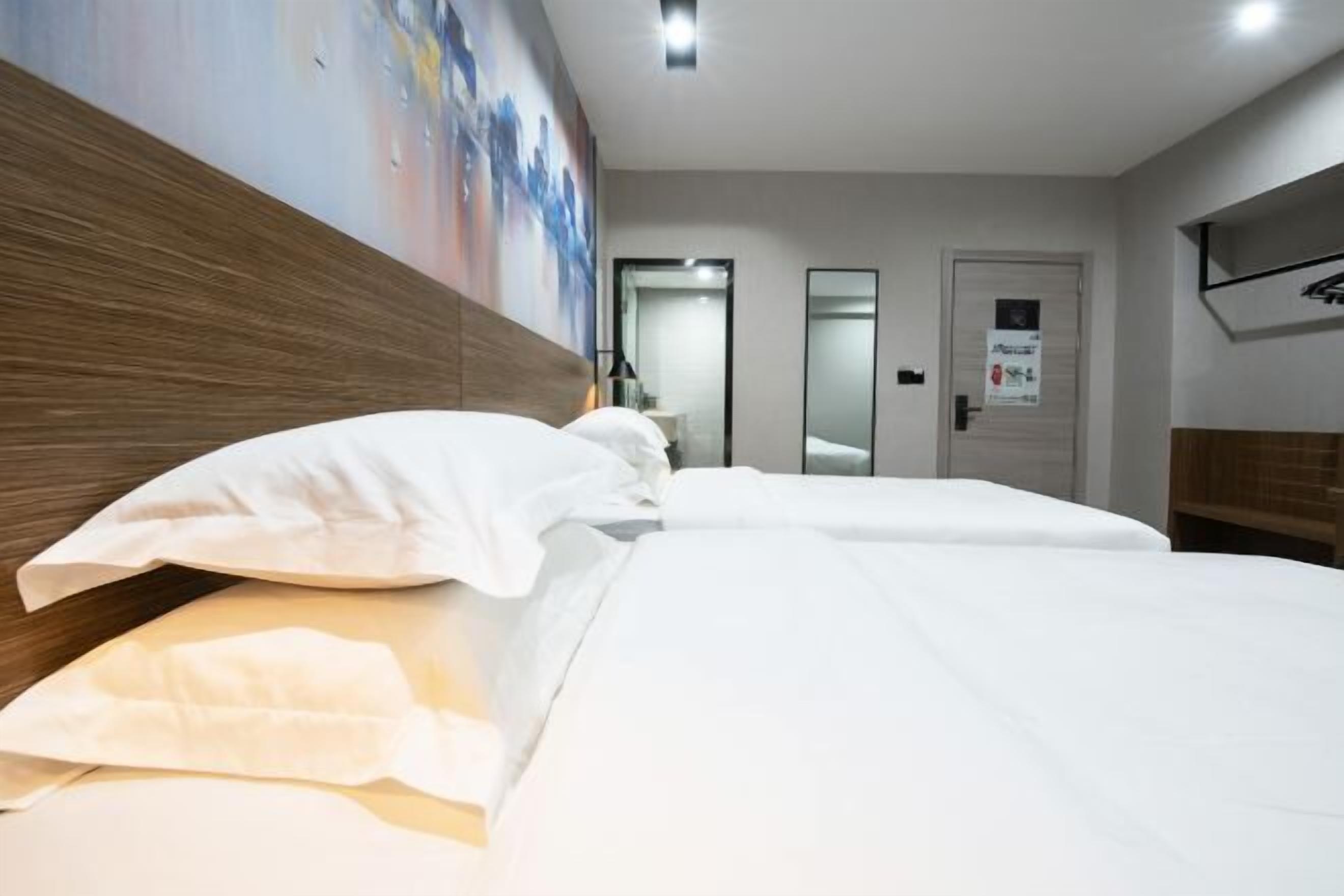 Een hotelkamer met een groot bed, een houten hoofdbord en een schilderij aan de muur.