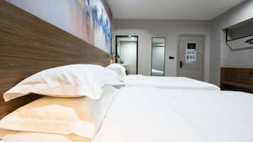 Een hotelkamer met een groot bed, een houten hoofdbord en een schilderij aan de muur.