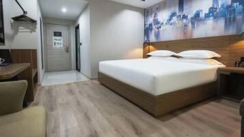 A modern hotel room with a wooden bed, a desk, and a cityscape mural on the wall.