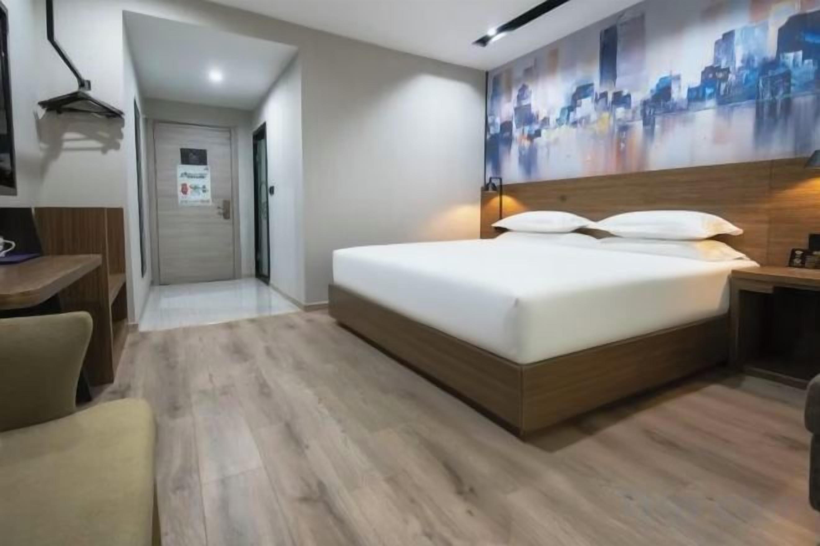 Una habitación de hotel con una cama de madera, un escritorio y un cuadro de paisaje urbano en la pared.