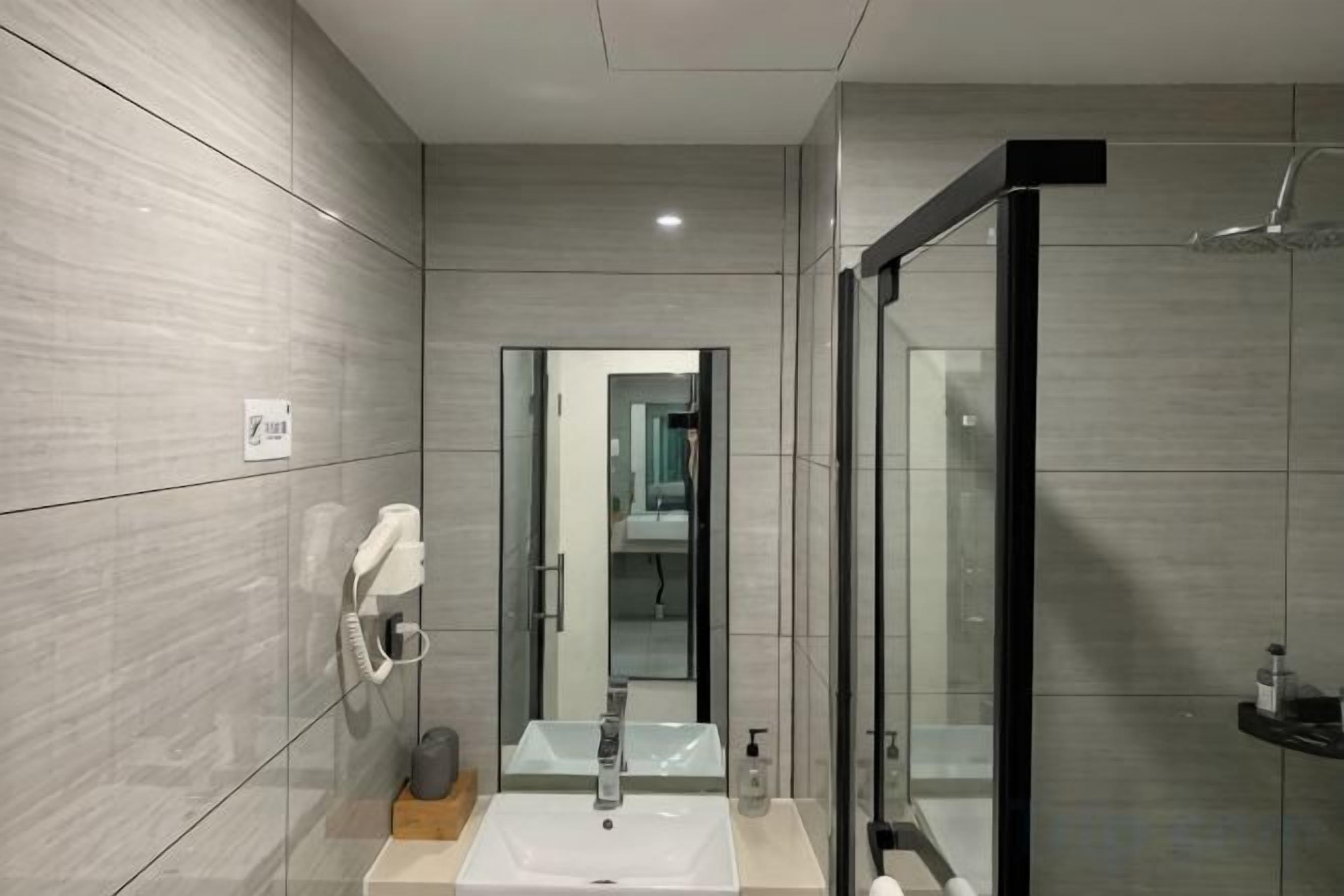A modern bathroom with a glass shower enclosure, a sink with a mirror, and a towel rack.